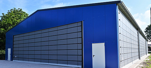 Frente abatible Lubratec en Soccerhalle Gran puerta plegable Lubratec en la fachada de un pabellón de fútbol azul