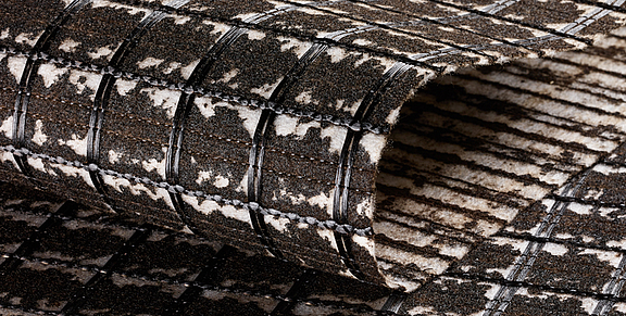 Refuerzo de asfalto SamiGrid® - vista de cerca del material Primer plano del compuesto SamiGrid® de rejilla de PVA y tejido no tejido saturado de betún